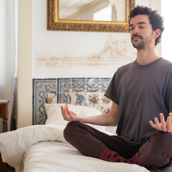 Man meditating on a bed