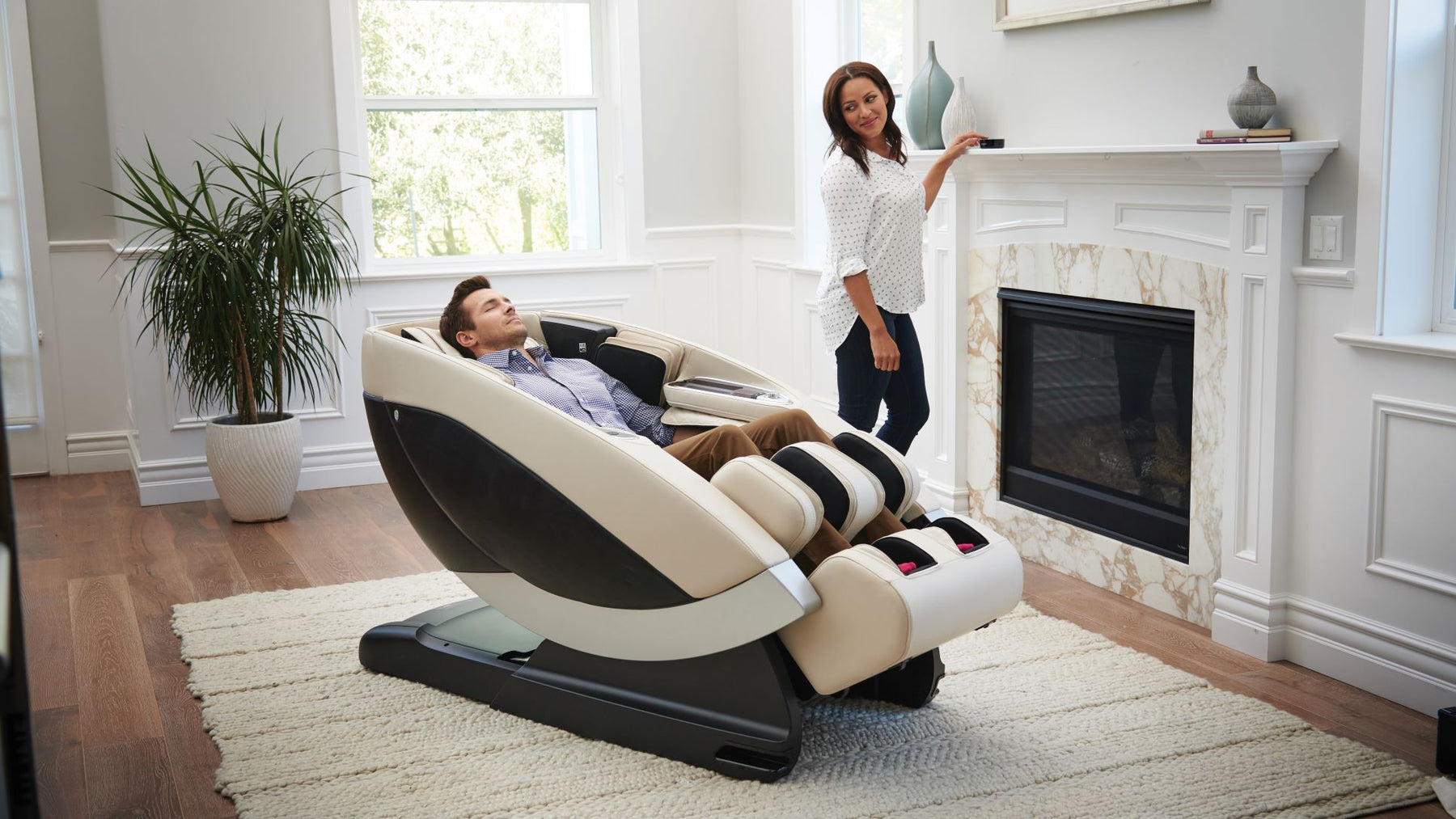 Man using a massage chair and a woman is standing next to him