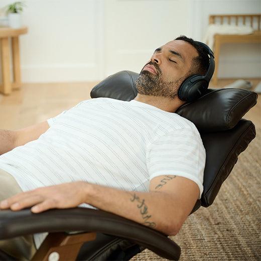 Man reclining in the Human Touch Perfect Chair and listening to music