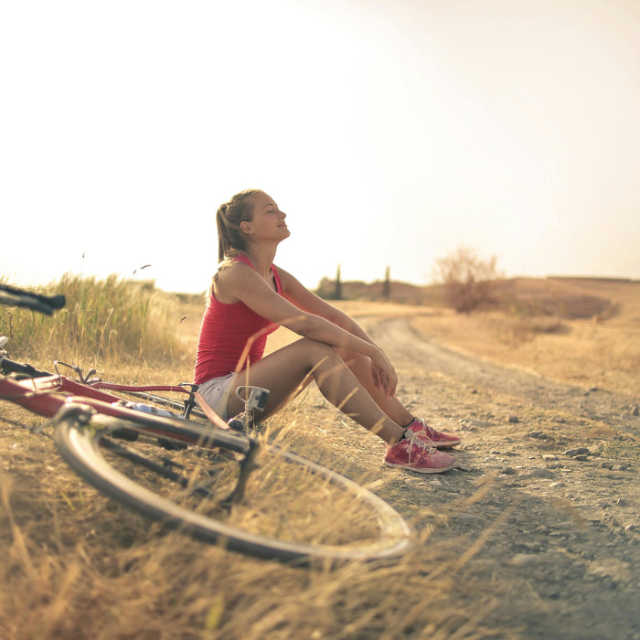 Woman sitting next to her bike on a dirt road