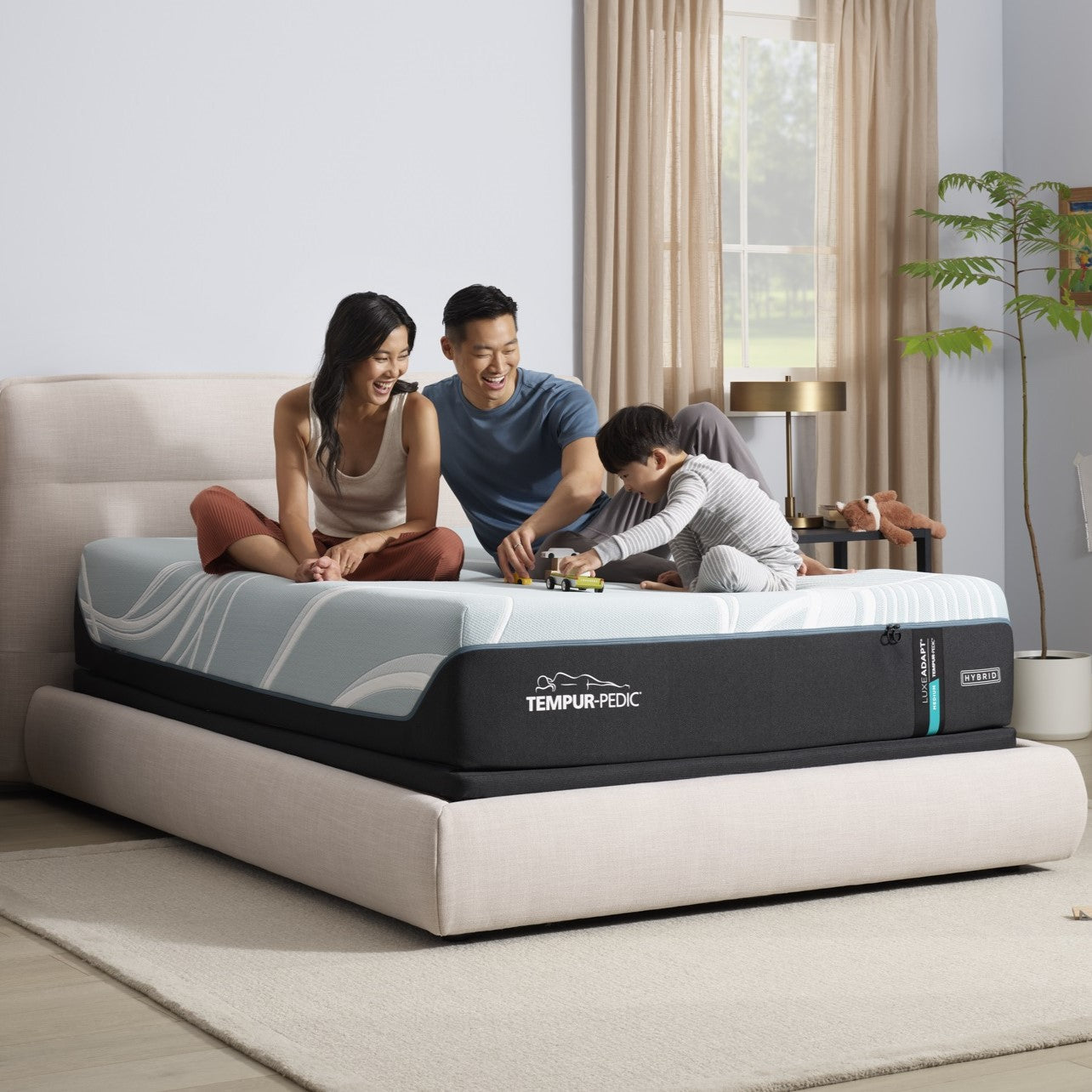 A family sitting on a Tempur Pedic mattresss in a bedroom setting.