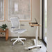 Float Mini Desk in an office setting with a warm wooden bench with a plant on top of it.