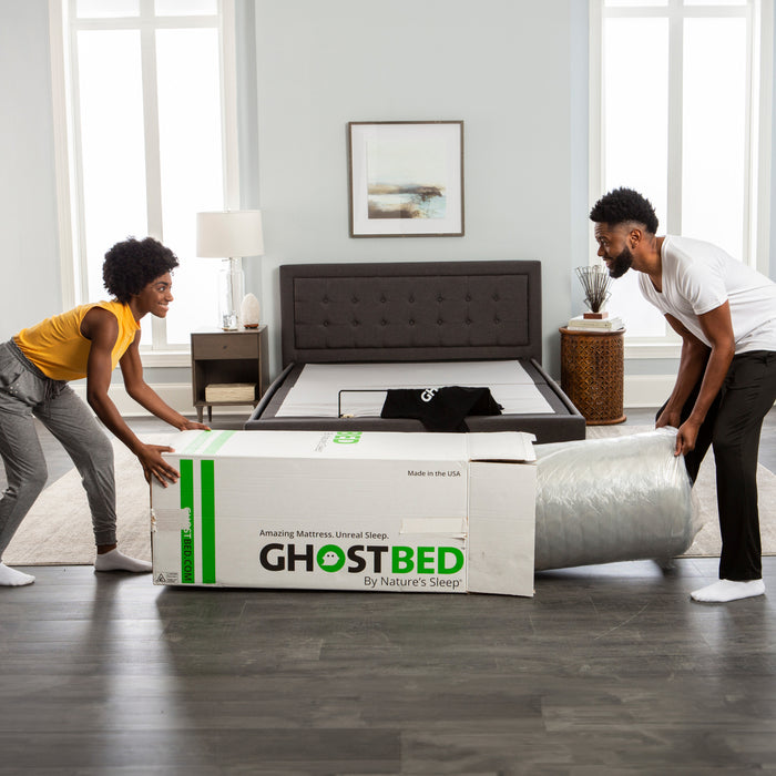 A woman and man removing a mattress from a Ghostbed delivery box.