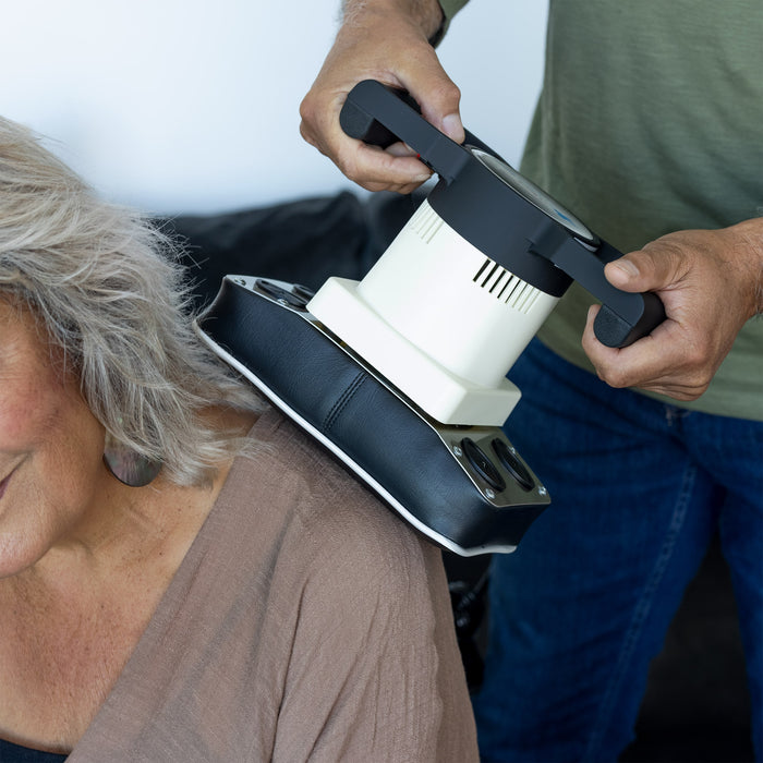 A woman using the Oscillatory Body Massager on her back.