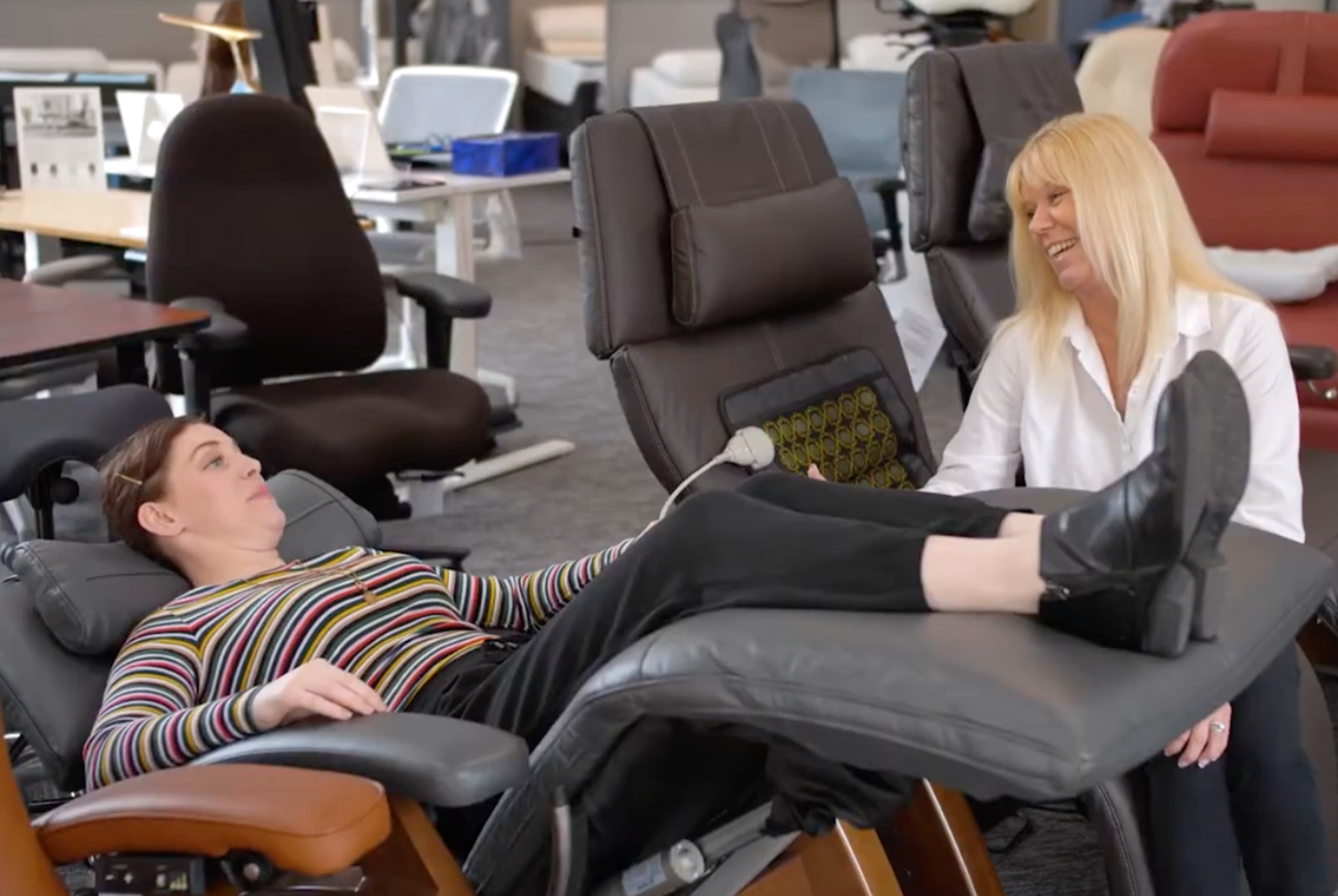 In store experience image of woman in a recliner being assisted by a sales associate.